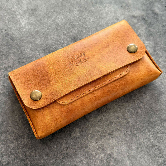 El yapımı, camel renkli deri tütün kesesi. Kişisel isim baskısı seçeneğiyle özel bir hediye arayanlar için ideal. Bolt Leather kalitesiyle doğal deri dokusu ve el işçiliği.